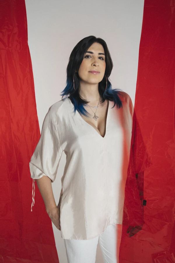 Ophelia con camisa blanca entre cortinas rojas. Vertical.