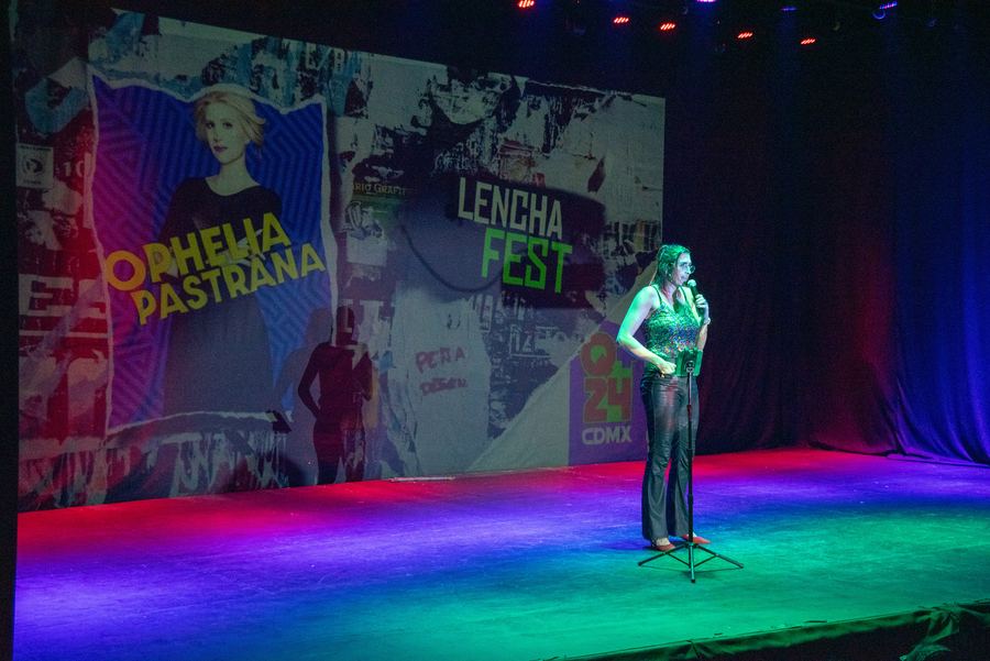 Ophelia en el escenario de Lenchafest con micrófono, pantalla con su nombre. Horizontal.
