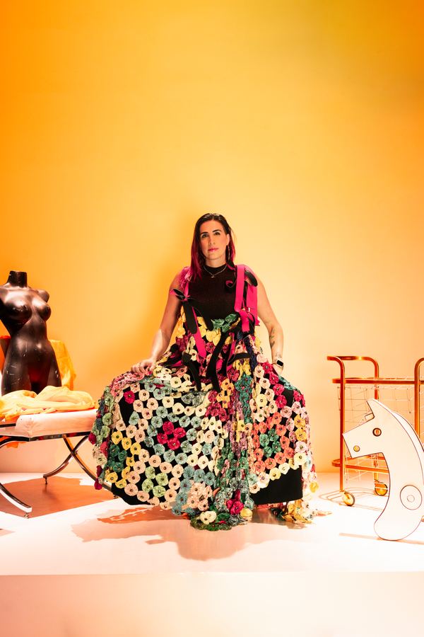 Ophelia sentada con falda de flores de colores, fondo amarillo.
