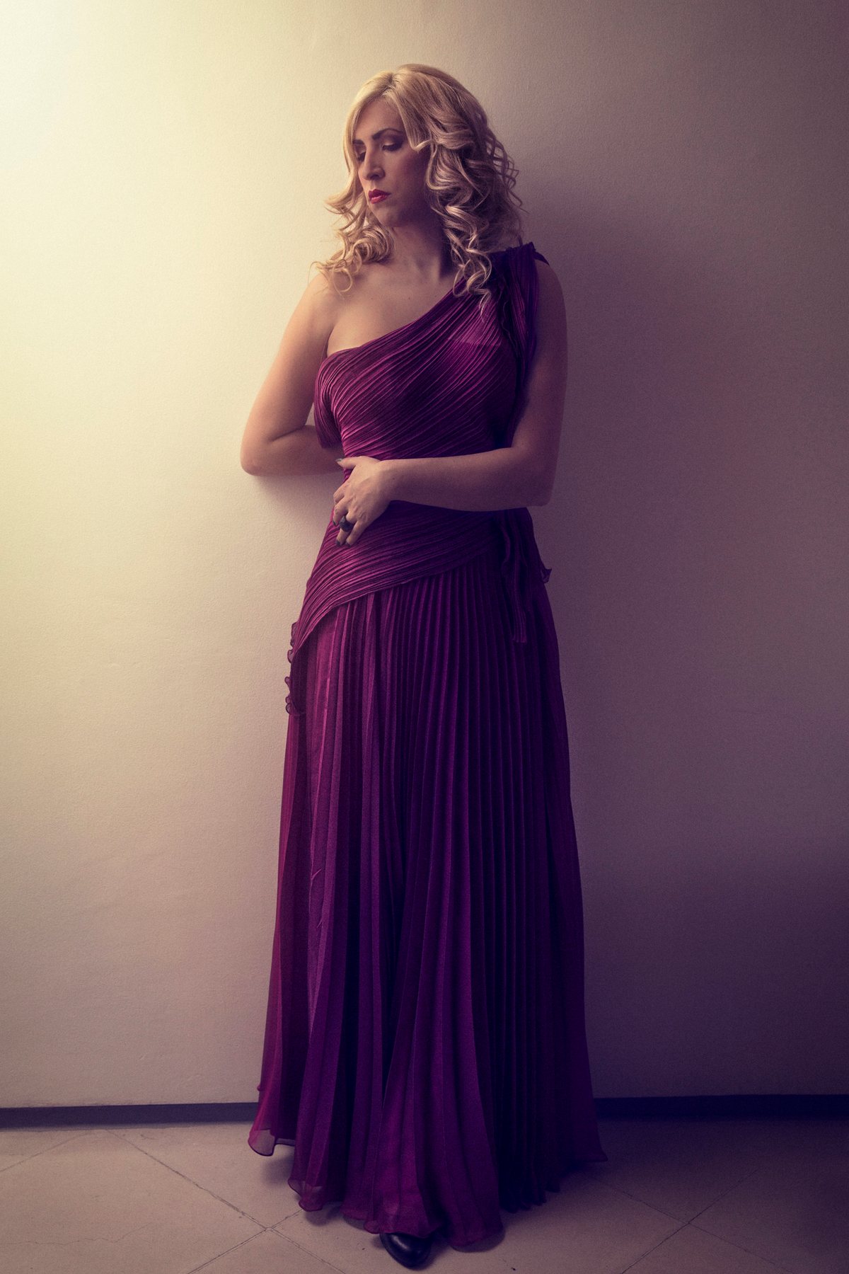 Ophelia de pie con vestido morado largo de un hombro.