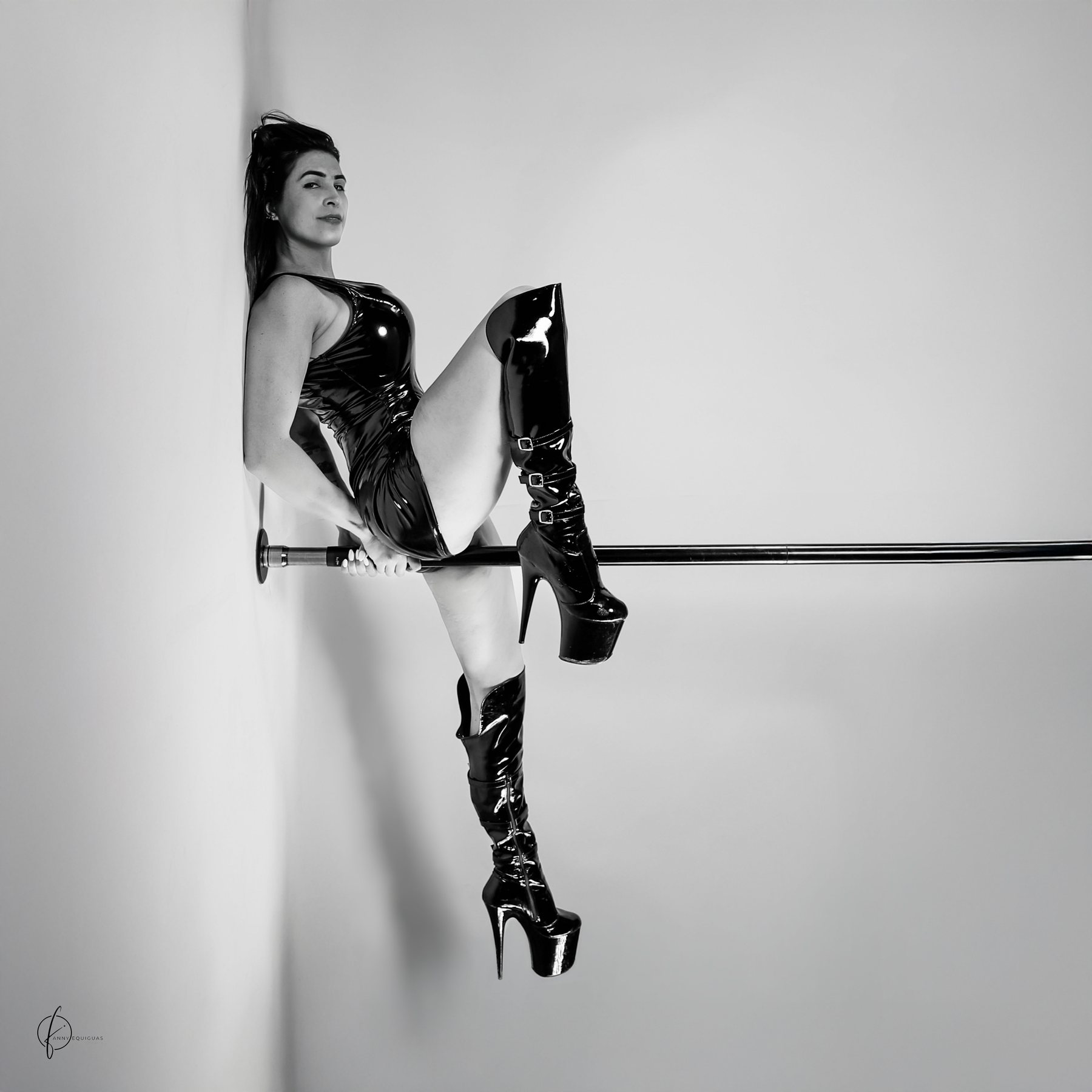 Ophelia sentada sobre una barra horizontal con botas altas, blanco y negro. Cuadrada.