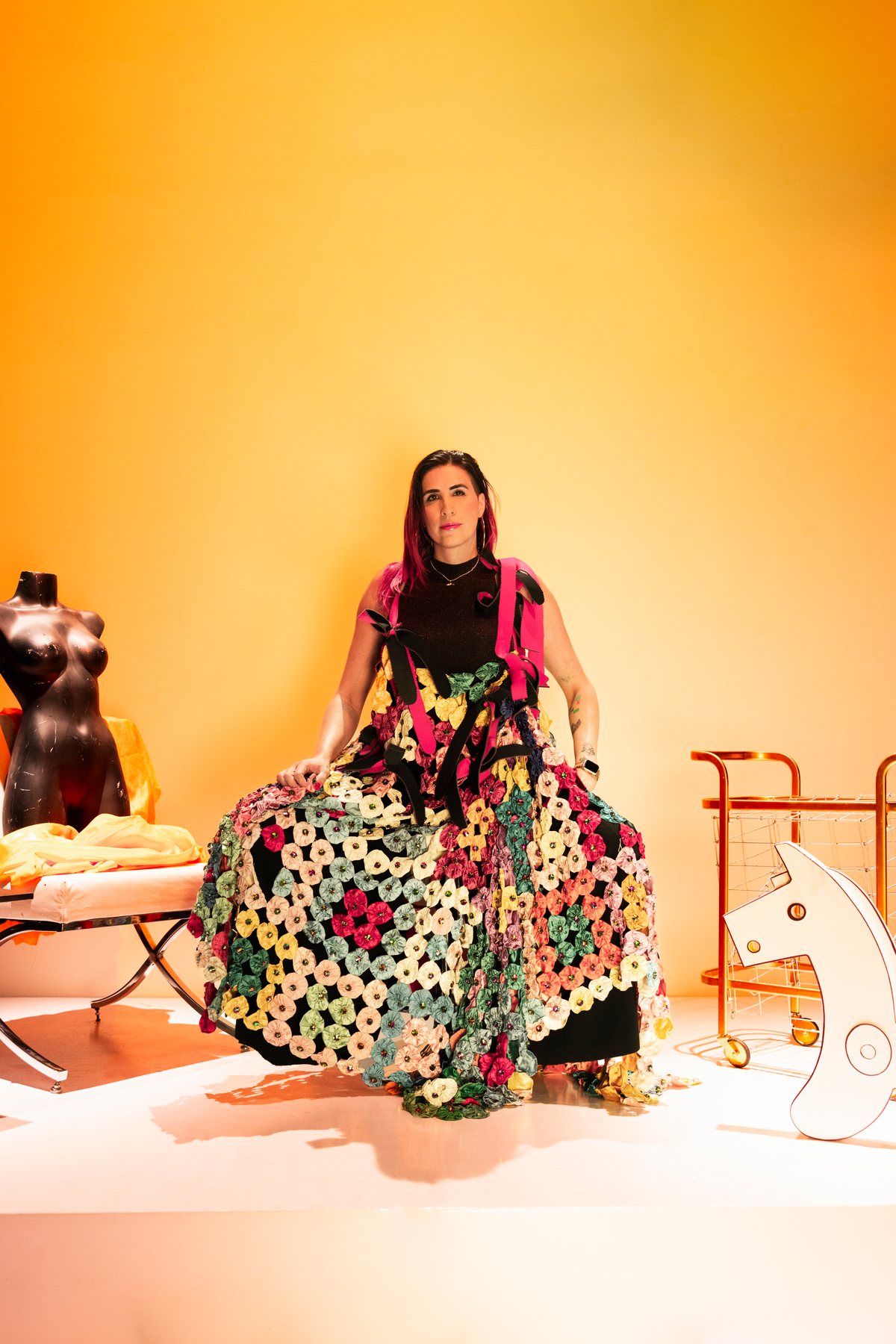 Ophelia sentada con falda de flores de colores, fondo amarillo.
